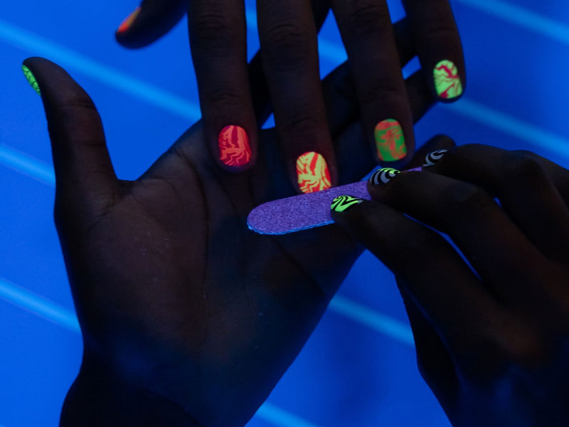 Hands with neon nail art under UV light