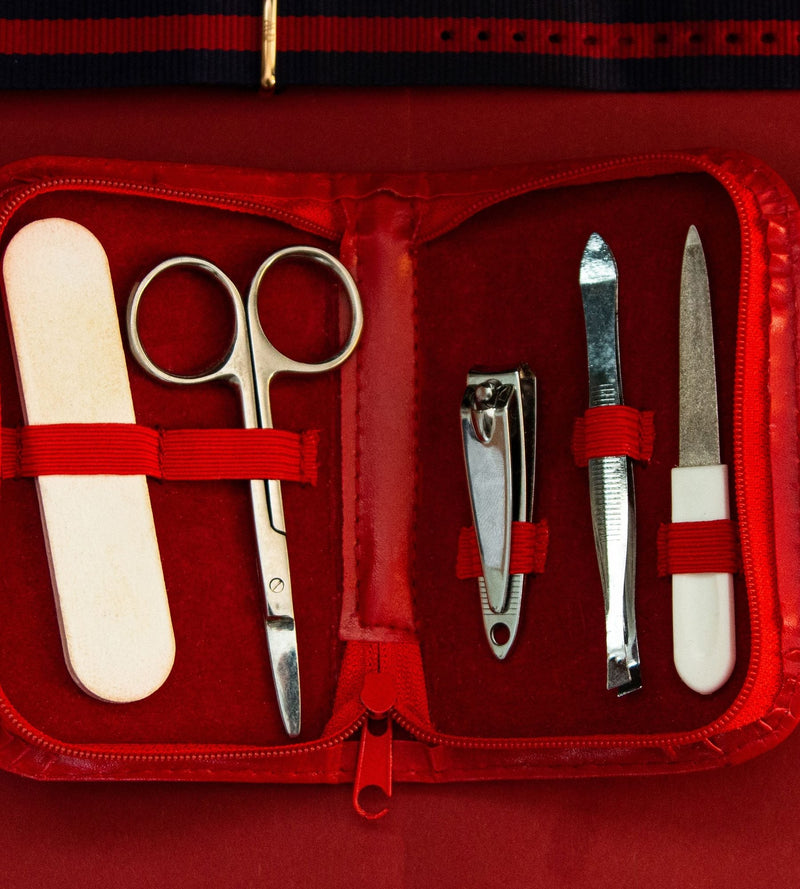Open red manicure kit with nail file, scissors, clippers and tweezers