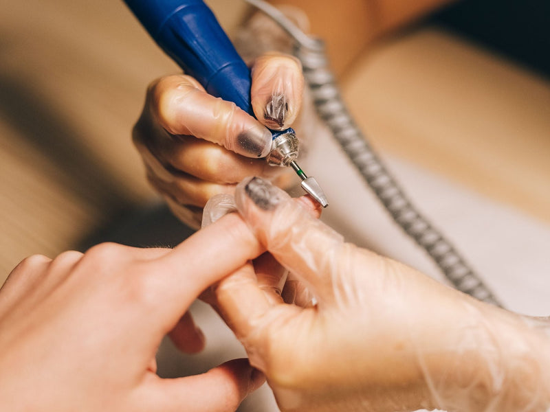Close-up of a nail drill with a bit working on a fingernail