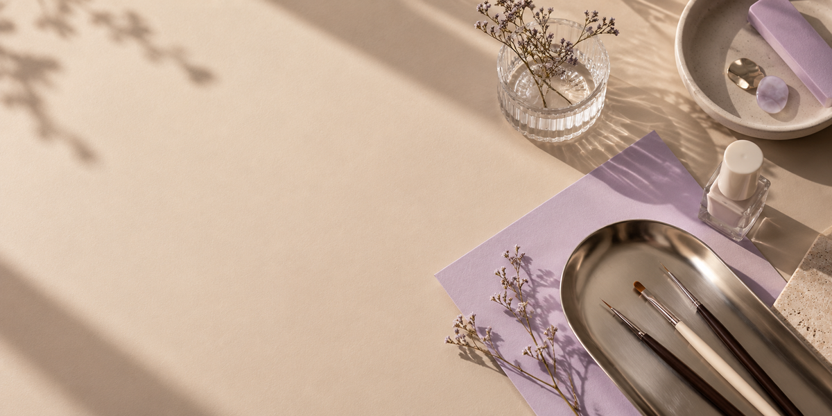 Nail art brushes, a lilac swatch card and a nail polish bottle on a warm oat desk