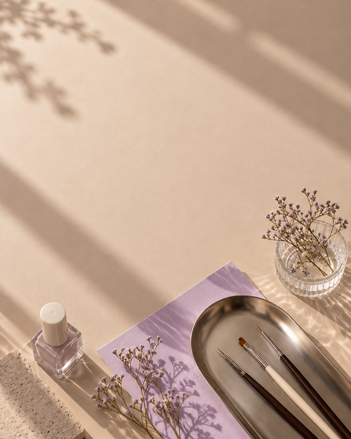 Nail art brushes and a polish bottle on an oat desk with lilac card